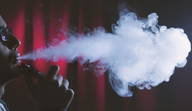 young, vaping man blows big cloud