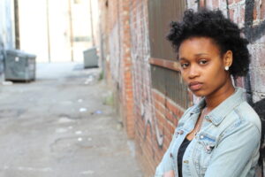 Depressed or annoyed black woman, leaning on a wall