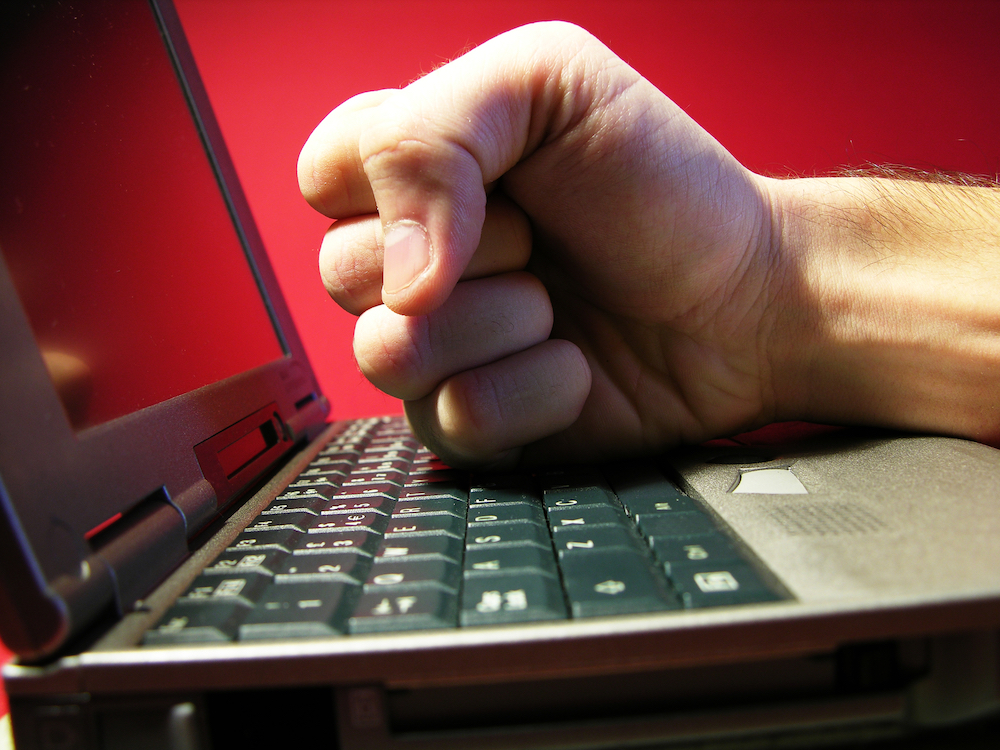 man hitting fist against computer