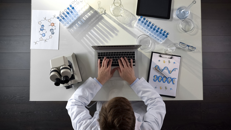 Genetics scientist typing on laptop, searches for link to psychotic episodes