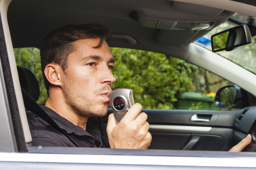 man blowing into a breathalyzer