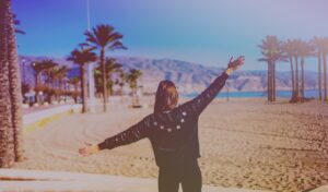 Woman with arms outstretched on a beach.