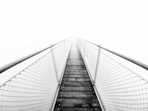 Grayscale of bridge vanishing into fog