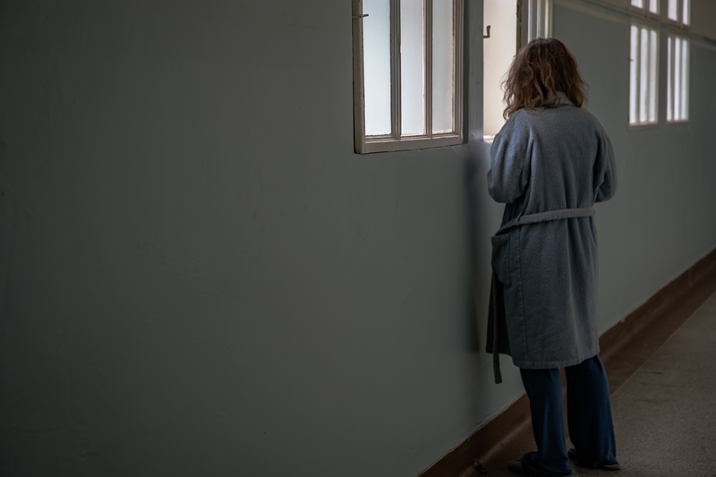 Woman looking out window in institutional hallway