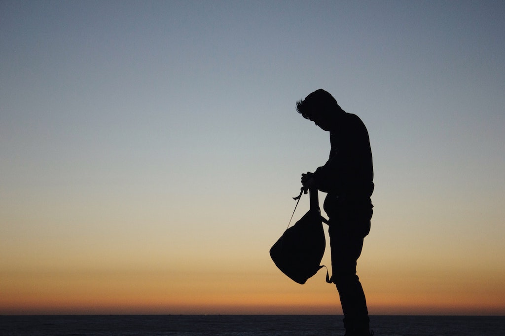 Man with backpack silhouetted against sky