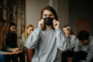 Woman holds mask to face in front of group without masks