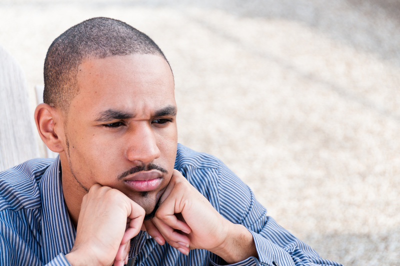 Young man, chin in hands, serious.