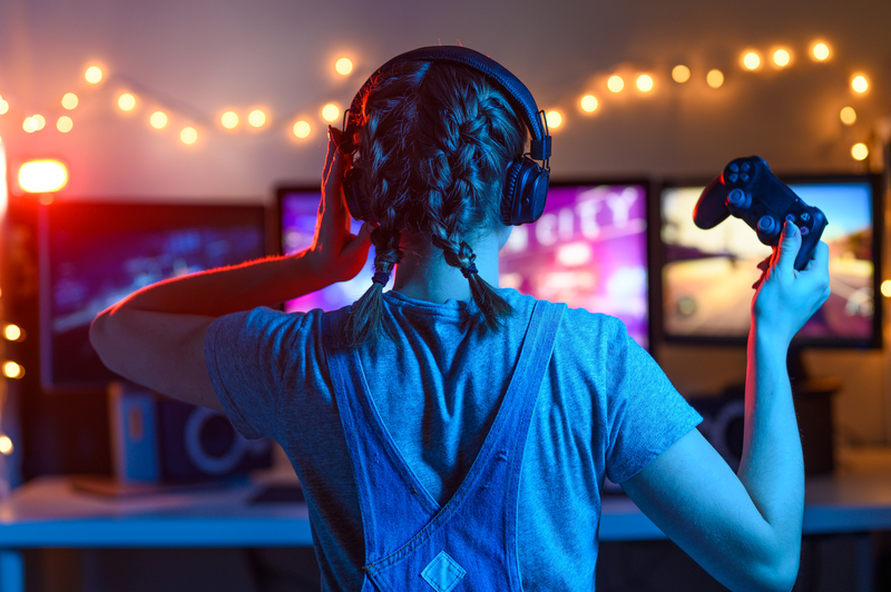 Woman holding game controller, looking at video screens