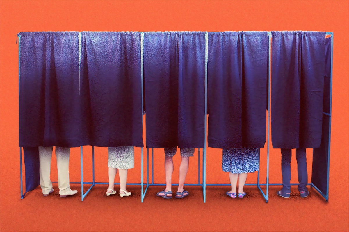 5 people seen standing in voting booths from the knees down, otherwise obscured by booth curtain