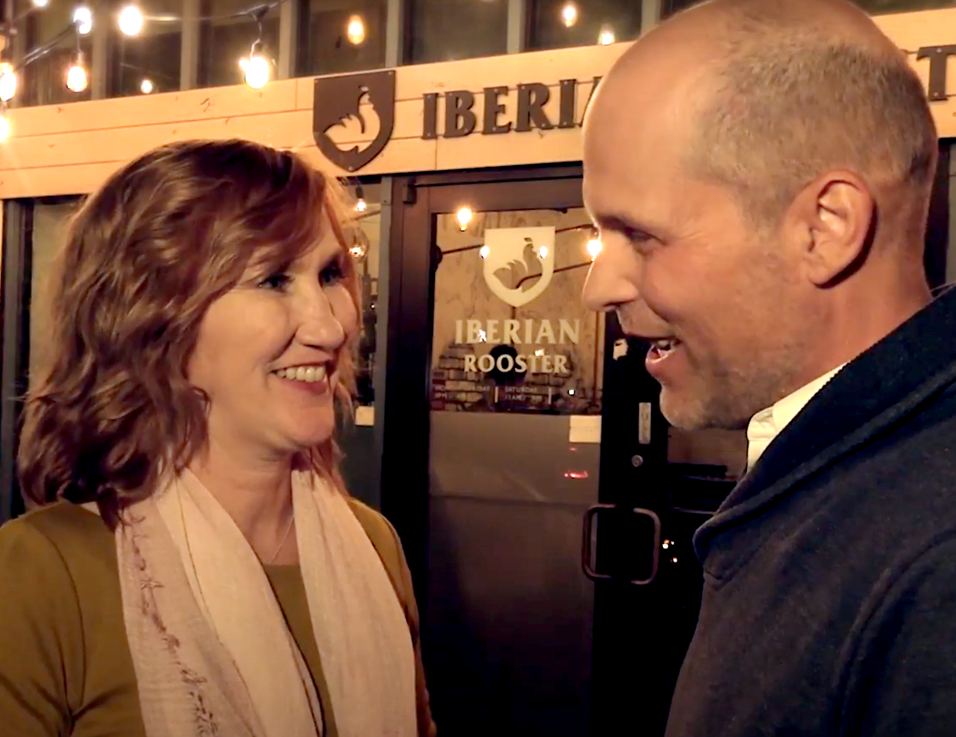 A woman and man stand close together, talking and smiling.