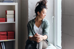 Young woman, thoughtful, looks out a window.