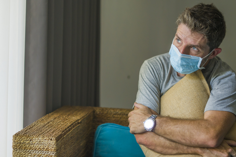 Man on couch wearing mask, looks depressed