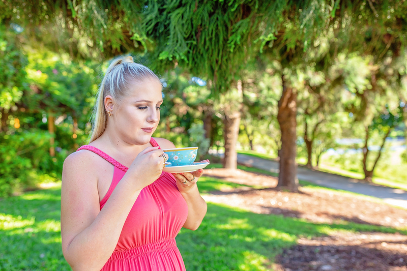 Woman in outdoors, garden area, sips tea