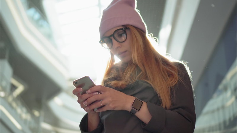 Young woman looks at phone, is inside a mall or building