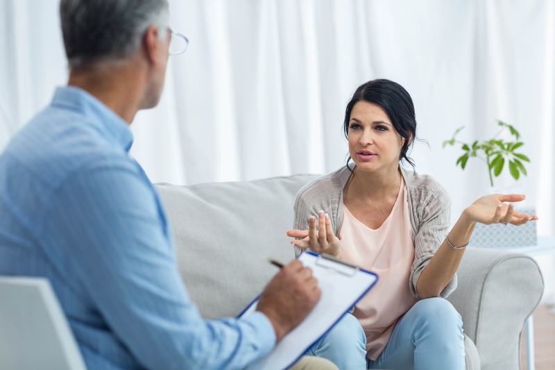 Woman sits on couch and talks to doctor who is facing her.
