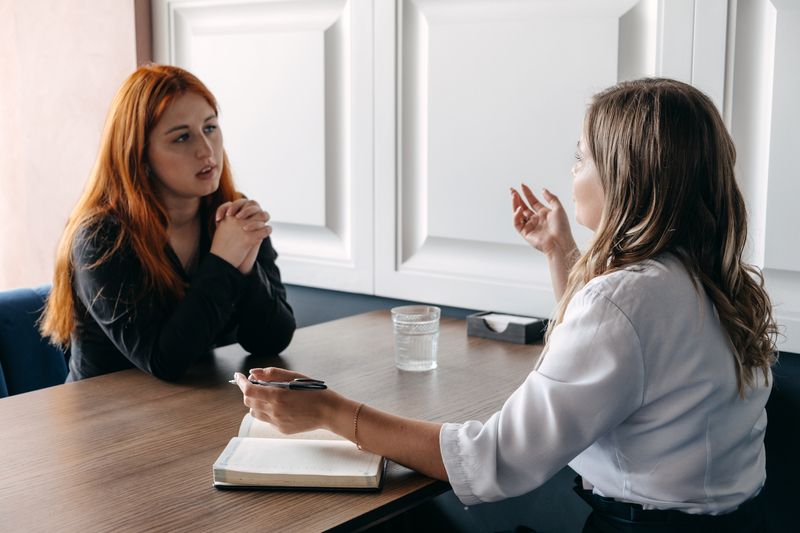 Two women talk over a table, one takes notes