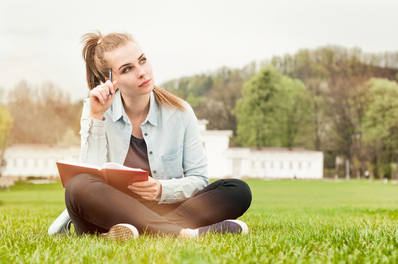 Woman sitting outside and writing in book.