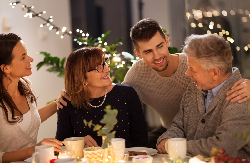 Four people (family?) sitting at table with coffee and smiling, talking